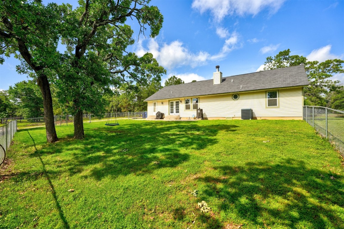6404 S Peebly Road, Newalla, OK 74857 back of property featuring a yard and central AC unit