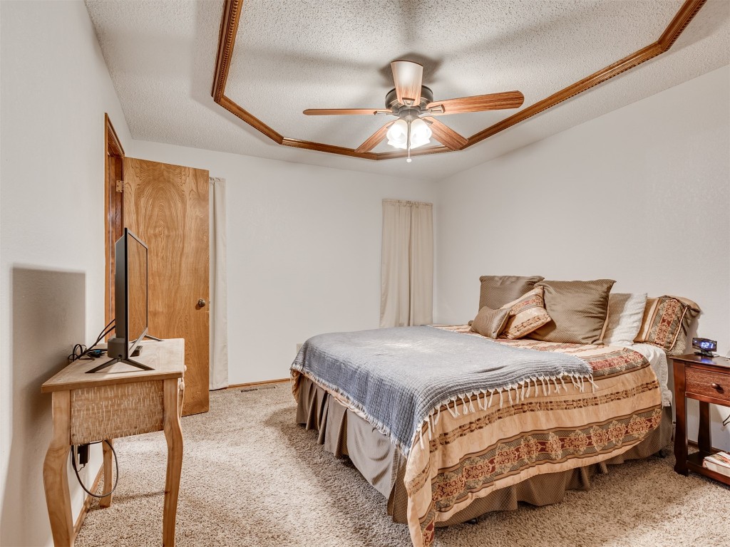 708 Waterview Road, Oklahoma City, OK 73170 bedroom with a tray ceiling, a textured ceiling, ceiling fan, and carpet