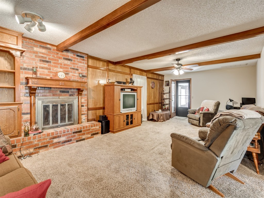 708 Waterview Road, Oklahoma City, OK 73170 living room with ceiling fan, carpet, a fireplace, a textured ceiling, and beam ceiling