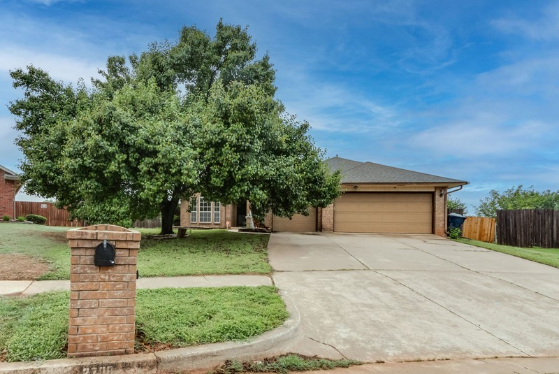 2708 NW 161st Street, Edmond, OK 73013 view of property hidden behind natural elements with a garage and a front lawn