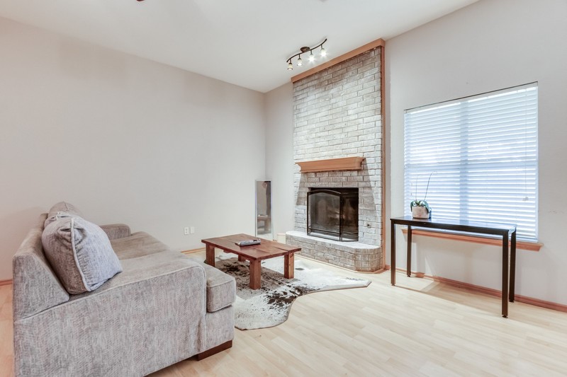 2708 NW 161st Street, Edmond, OK 73013 living room with brick wall, light hardwood / wood-style flooring, rail lighting, and a fireplace