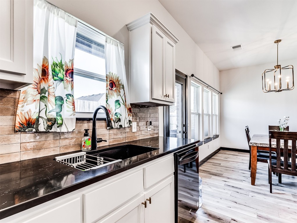 12613 NW 4th Terrace, Yukon, OK 73099 kitchen with decorative light fixtures, light wood-type flooring, white cabinetry, sink, and tasteful backsplash