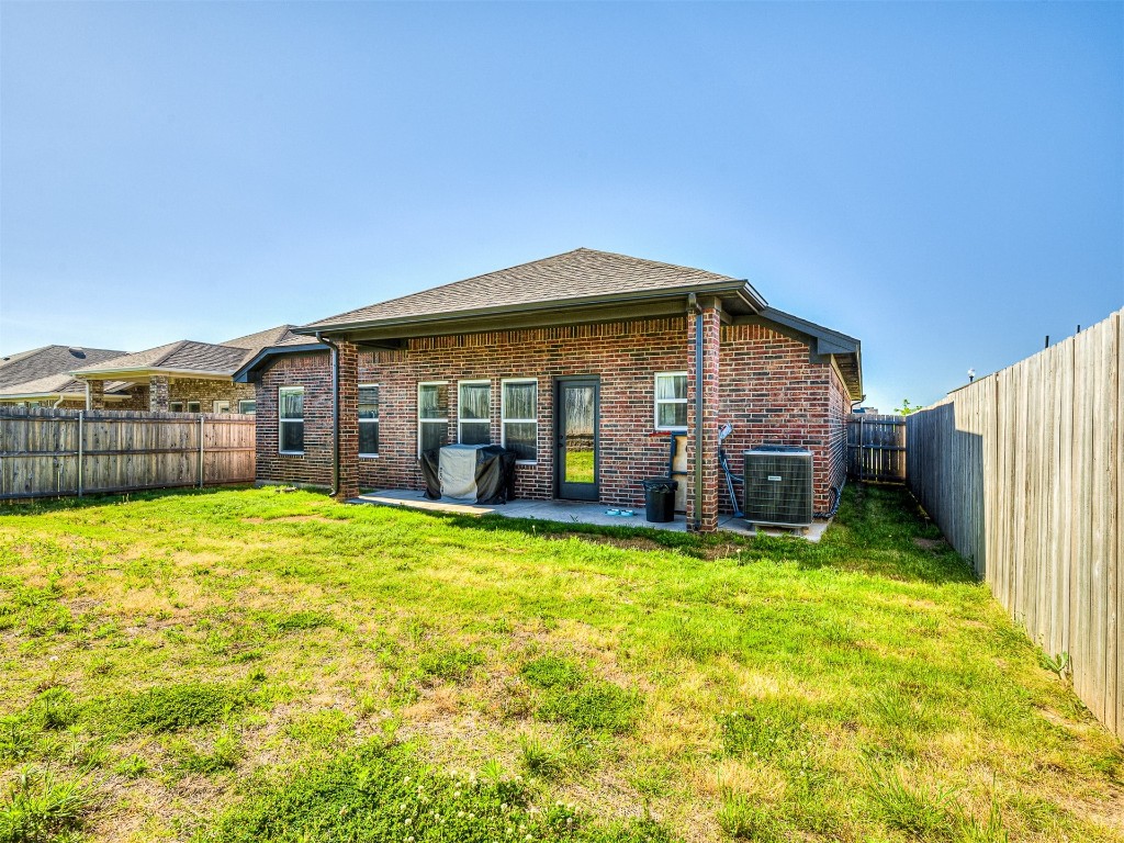 12613 NW 4th Terrace, Yukon, OK 73099 back of property with a patio, a yard, and central air condition unit