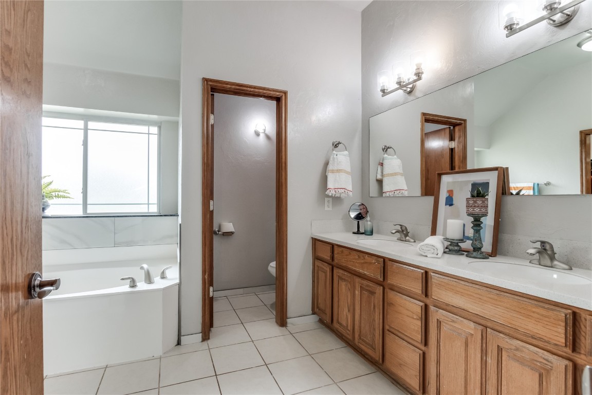9212 SW 26th Street, Oklahoma City, OK 73128 bathroom featuring large vanity, toilet, a tub, tile floors, and dual sinks