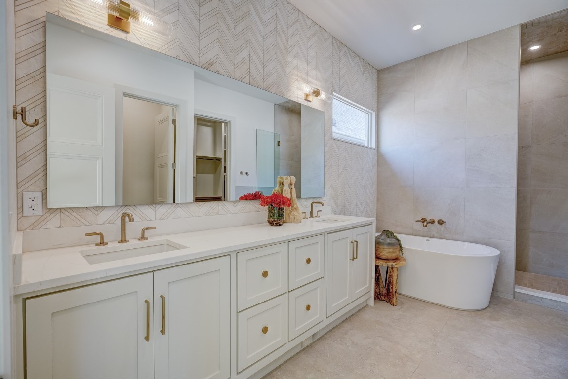 908 NW 44th Street, Oklahoma City, OK 73118 bathroom featuring double sink vanity, tile walls, backsplash, a tub, and tile floors