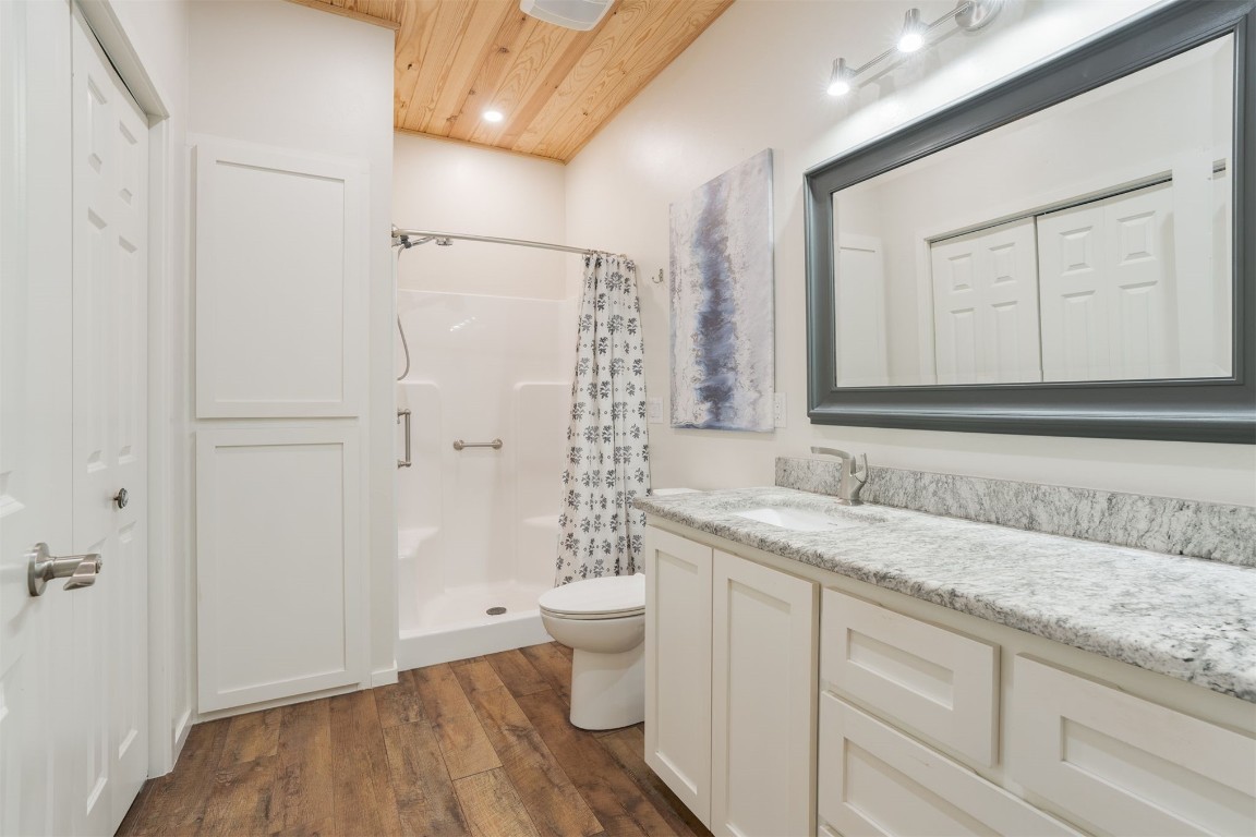 17000 N Anderson Road, Arcadia, OK 73007 bathroom featuring walk in shower, vanity, wood ceiling, hardwood / wood-style flooring, and toilet