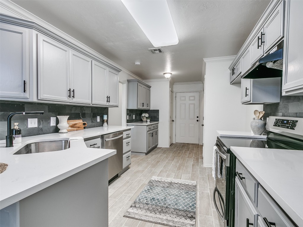 1473 N 1st Street, Harrah, OK 73045 kitchen featuring tasteful backsplash, stainless steel appliances, ornamental molding, and gray cabinetry