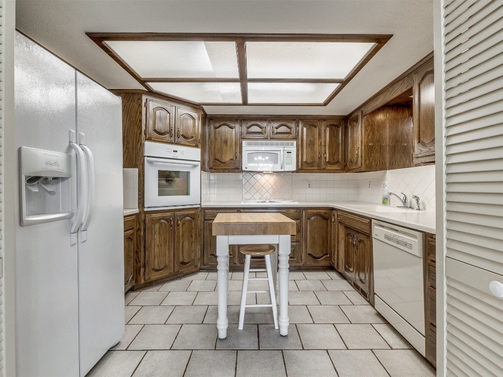 9610 Warringer Court, Oklahoma City, OK 73162 kitchen featuring light tile flooring, white appliances, backsplash, and sink