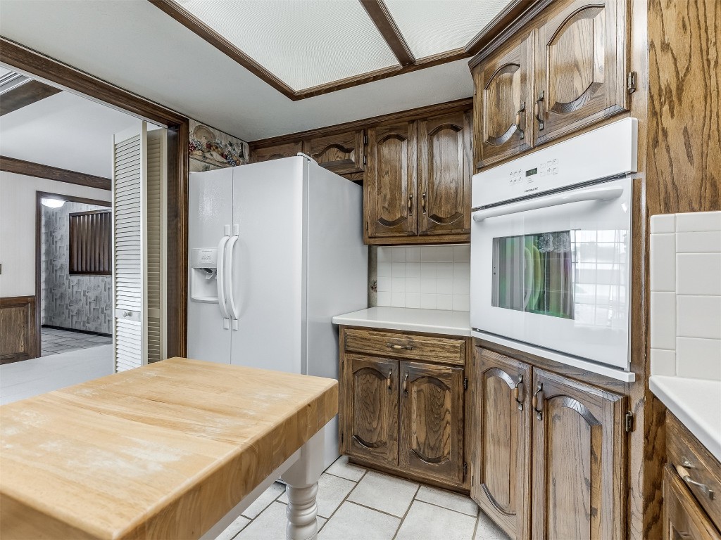 9610 Warringer Court, Oklahoma City, OK 73162 kitchen featuring tasteful backsplash, white appliances, and light tile floors