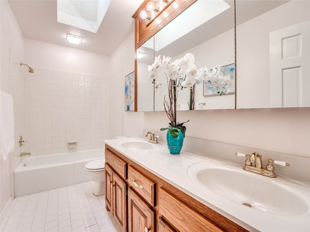 2501 Julies Trail, Edmond, OK 73012 full bathroom featuring vanity with extensive cabinet space, tiled shower / bath combo, tile floors, dual sinks, and toilet