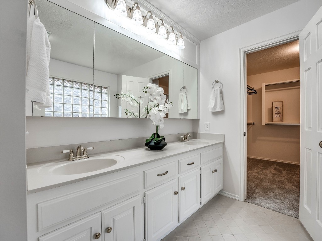 2501 Julies Trail, Edmond, OK 73012 bathroom featuring tile floors, a textured ceiling, and double sink vanity