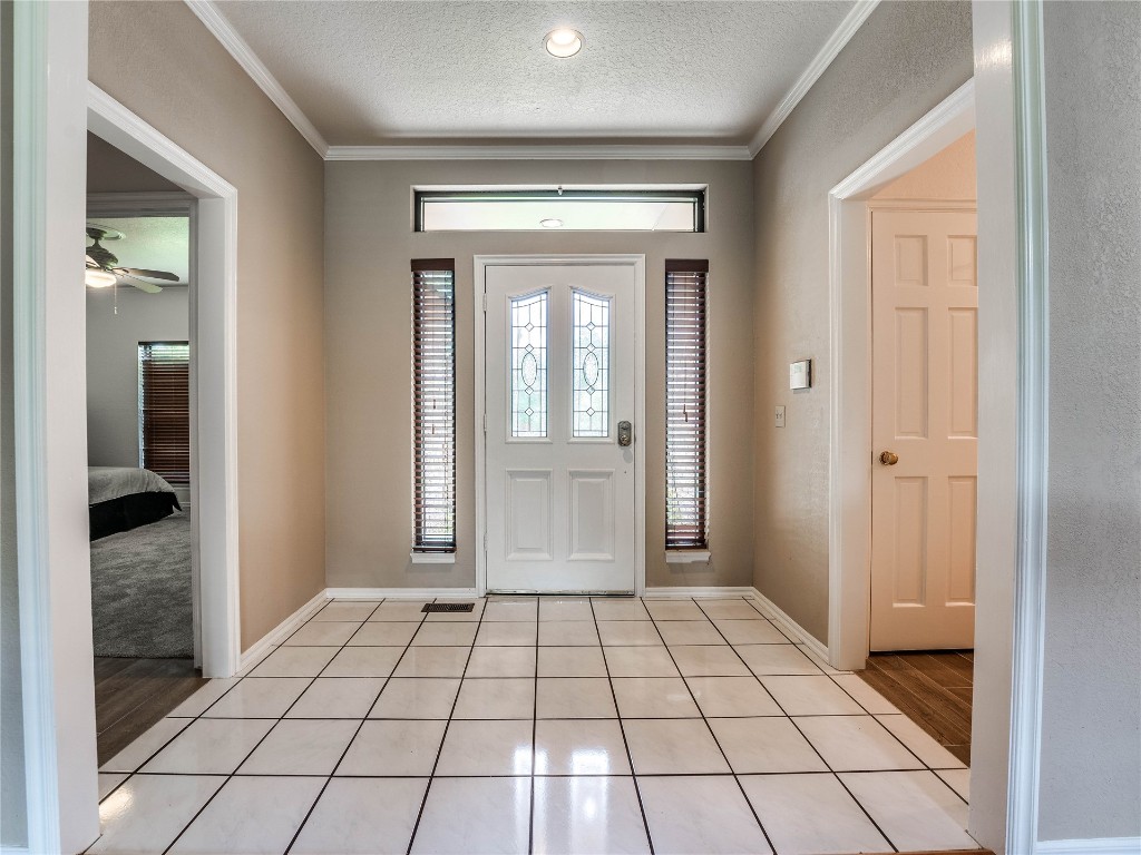 2501 Julies Trail, Edmond, OK 73012 foyer entrance featuring crown molding, light hardwood / wood-style flooring, ceiling fan, and a textured ceiling