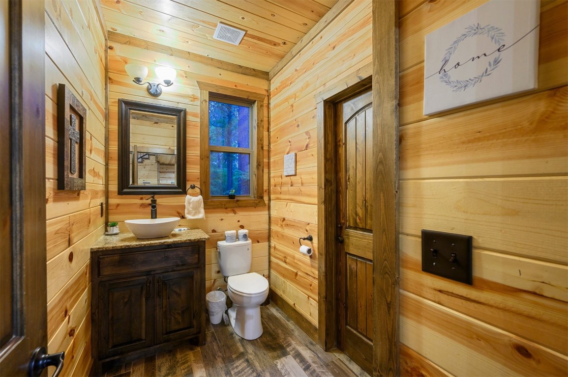 335 Mountain Pine Trail, Broken Bow, OK 74728 bathroom featuring hardwood / wood-style flooring, toilet, and wooden walls