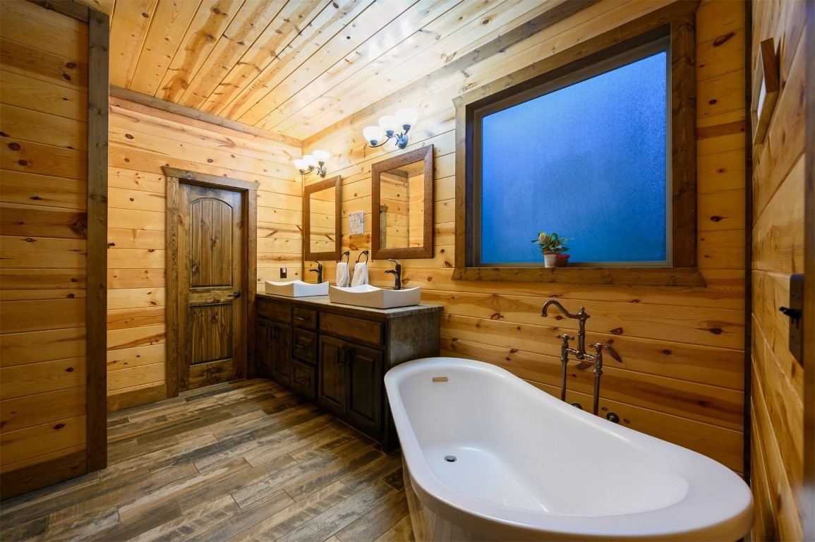 335 Mountain Pine Trail, Broken Bow, OK 74728 bathroom featuring a washtub, wood walls, wood-type flooring, and vanity