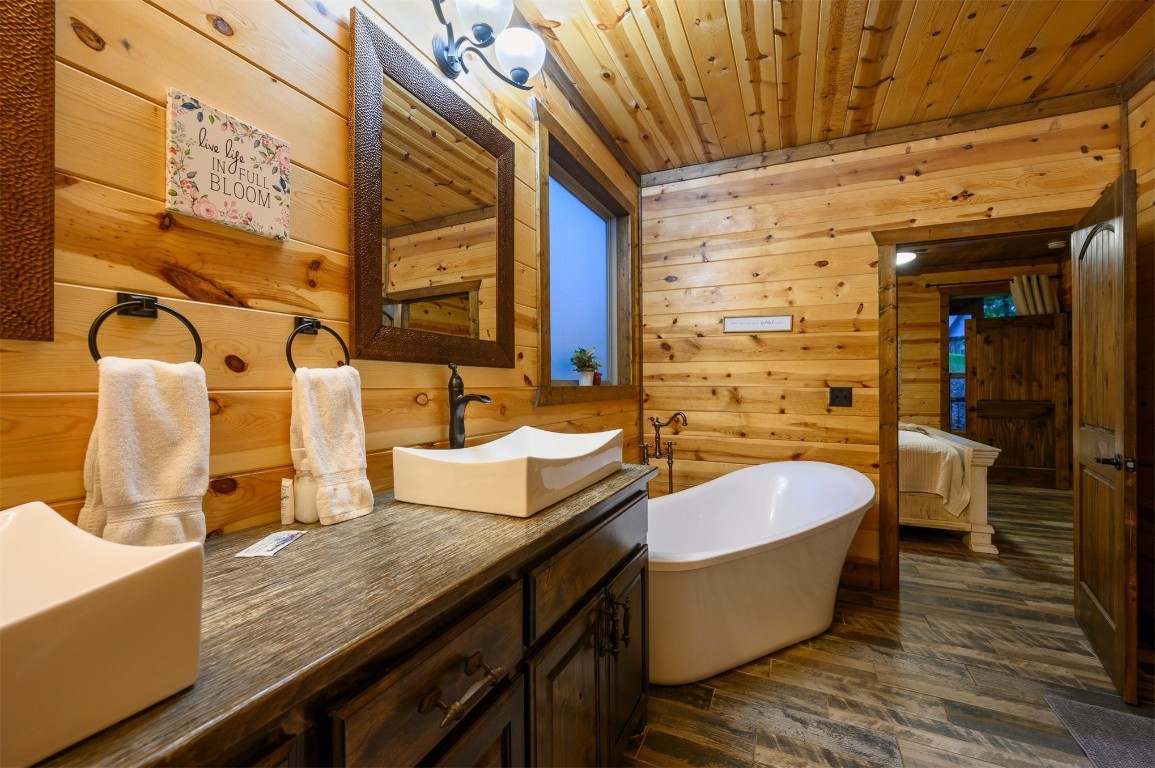 335 Mountain Pine Trail, Broken Bow, OK 74728 bathroom featuring vanity with extensive cabinet space, a bathtub, hardwood / wood-style flooring, wooden walls, and wood ceiling