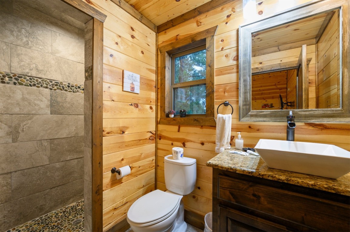 335 Mountain Pine Trail, Broken Bow, OK 74728 bathroom featuring wood ceiling, vanity with extensive cabinet space, toilet, and wooden walls