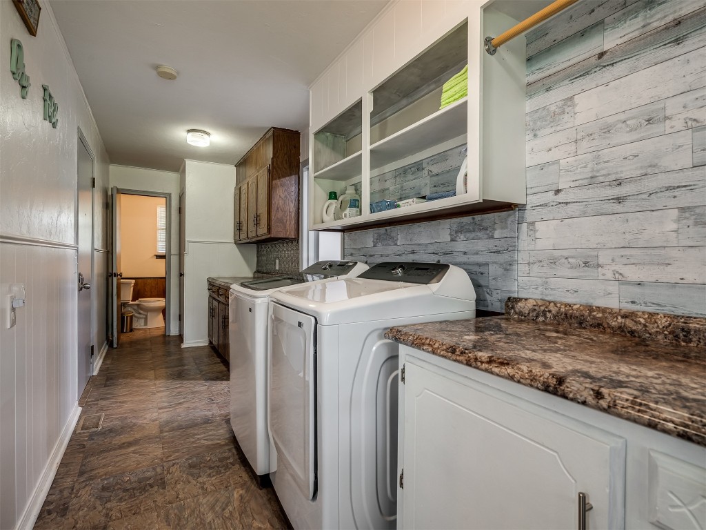 102199 S Highway 18, Meeker, OK 74855 laundry room with wood walls, dark tile floors, washing machine and clothes dryer, and cabinets