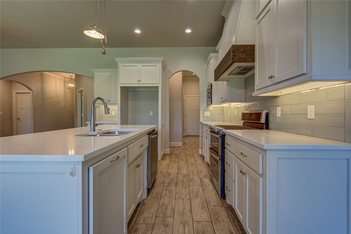 201 Casey Lane, Washington, OK 73093 kitchen featuring appliances with stainless steel finishes, sink, backsplash, an island with sink, and premium range hood
