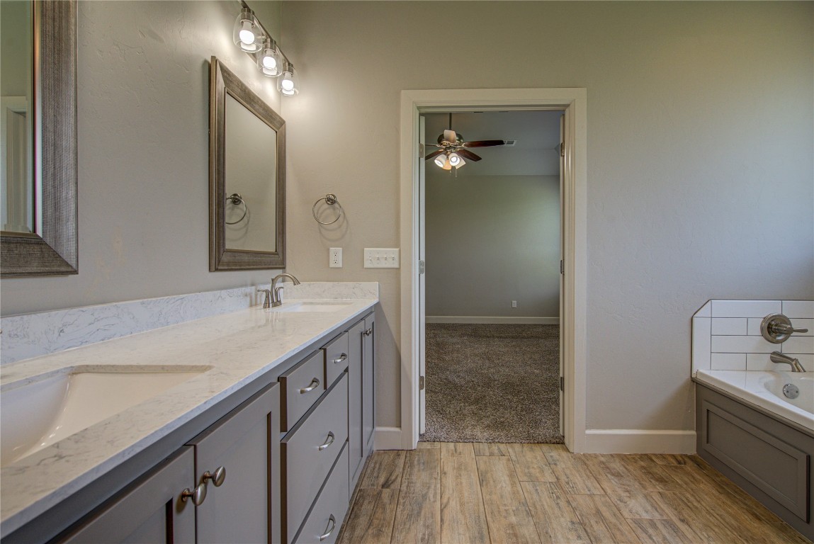 201 Casey Lane, Washington, OK 73093 bathroom with ceiling fan, a washtub, oversized vanity, double sink, and wood-type flooring
