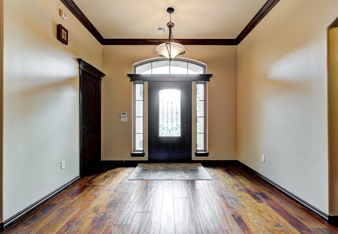 1713 Rain Tree Lane, Choctaw, OK 73020 entryway with crown molding and dark hardwood / wood-style floors