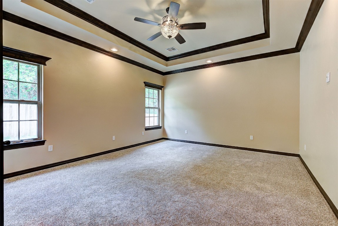 1713 Rain Tree Lane, Choctaw, OK 73020 spare room featuring plenty of natural light, ceiling fan, crown molding, a tray ceiling, and carpet floors