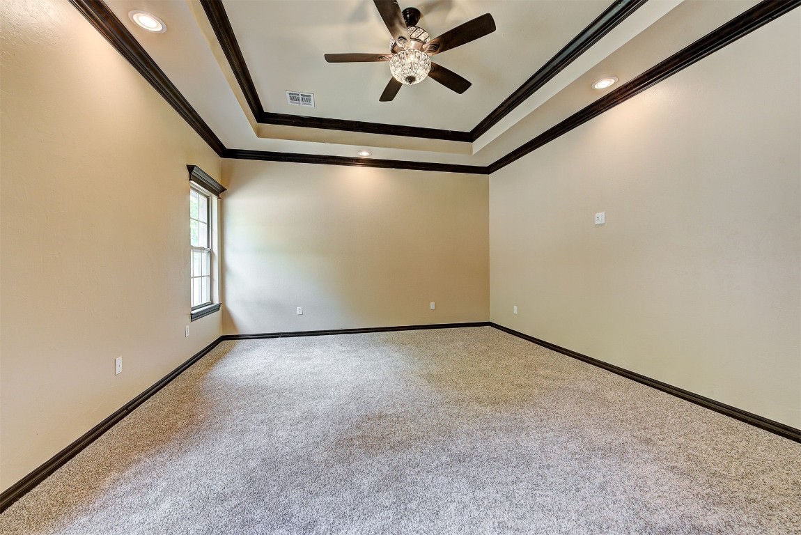 1713 Rain Tree Lane, Choctaw, OK 73020 carpeted spare room featuring crown molding, ceiling fan, and a tray ceiling