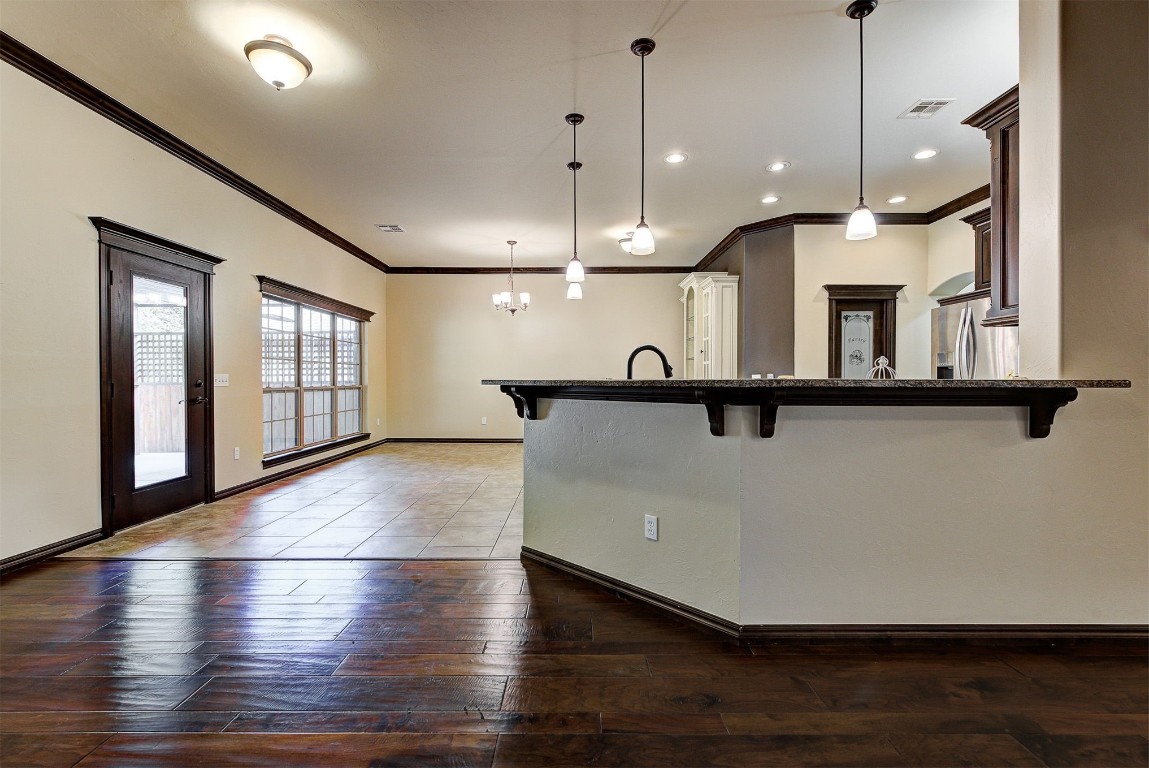 1713 Rain Tree Lane, Choctaw, OK 73020 kitchen featuring a kitchen breakfast bar, pendant lighting, stainless steel refrigerator with ice dispenser, hardwood / wood-style floors, and a notable chandelier