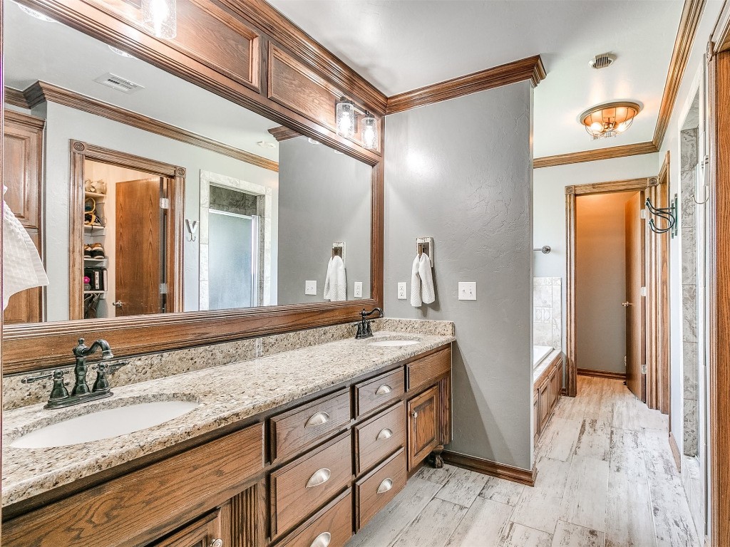835 County Street 2922, Tuttle, OK 73089 bathroom with oversized vanity, a bath, crown molding, double sink, and hardwood / wood-style floors