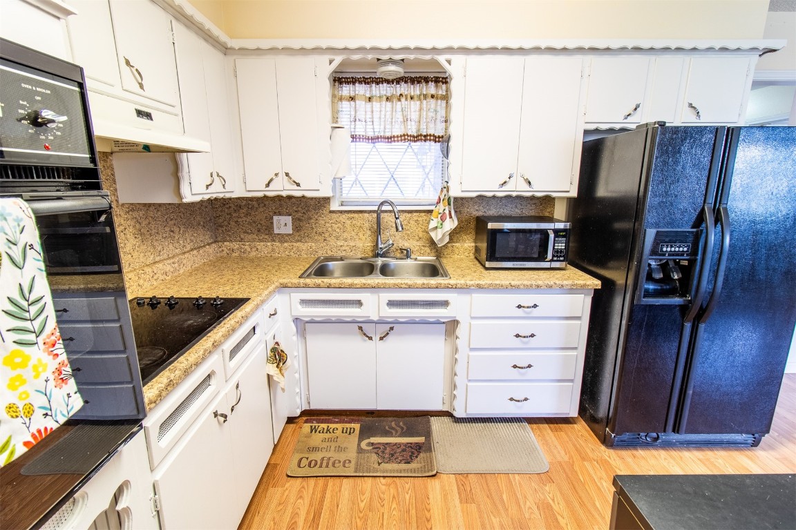 4704 Leslie Drive, Del City, OK 73115 kitchen with tasteful backsplash, white cabinetry, custom range hood, and black appliances