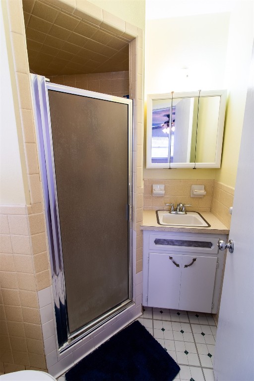 4704 Leslie Drive, Del City, OK 73115 bathroom featuring tile walls, a shower with door, tile floors, and vanity