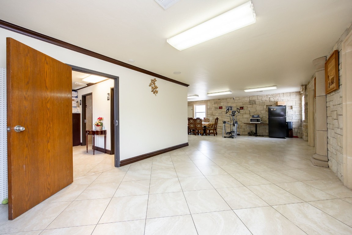 313 E 33rd Street, Edmond, OK 73013 unfurnished living room with light tile floors and ornamental molding