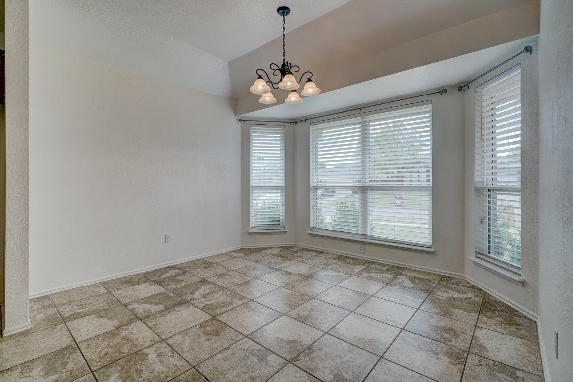 3509 Shona Way, Norman, OK 73069 empty room featuring a notable chandelier, light tile floors, and lofted ceiling
