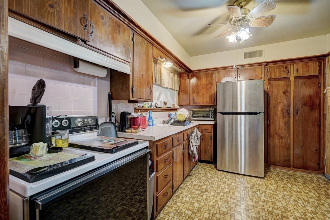 3809 NW 57th Street, Oklahoma City, OK 73112 kitchen with backsplash, light tile floors, stainless steel fridge, electric range, and ceiling fan