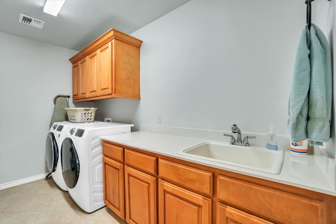3901 Heritage Trail, Altus, OK 73521 laundry area with light tile flooring, separate washer and dryer, hookup for a washing machine, sink, and cabinets