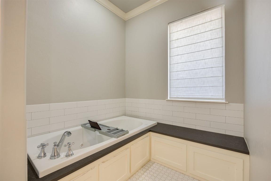 6332 Wentworth Drive, Edmond, OK 73025 bathroom featuring a bath, crown molding, and tile floors