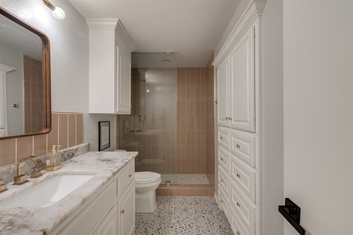 6001 Acorn Drive, Oklahoma City, OK 73151 bathroom featuring tasteful backsplash, toilet, tiled shower, and vanity