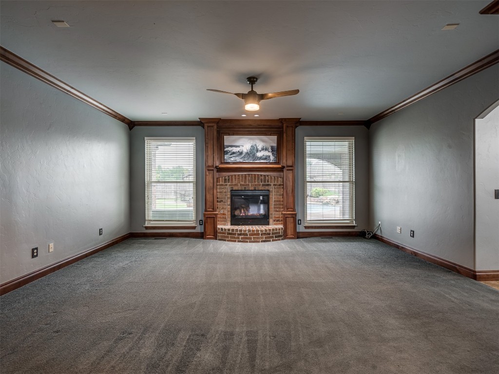 1517 SW 132nd Street, Oklahoma City, OK 73170 unfurnished living room featuring a healthy amount of sunlight, ceiling fan, a brick fireplace, and carpet flooring