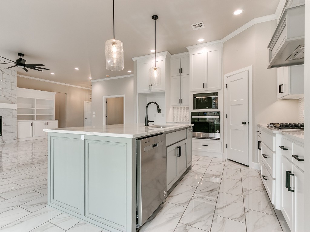 500 Carlow Way, Yukon, OK 73099 kitchen featuring pendant lighting, a kitchen island with sink, white cabinets, ceiling fan with notable chandelier, and appliances with stainless steel finishes