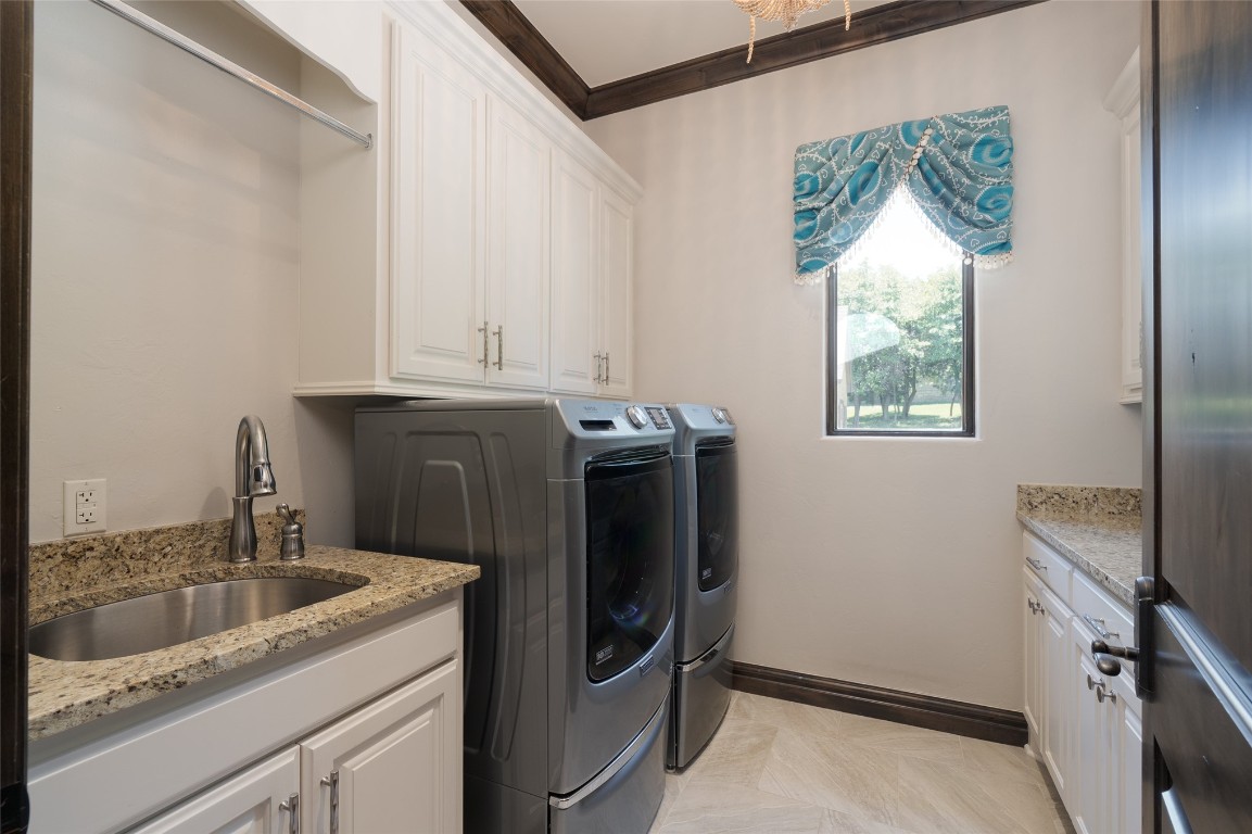 1200 Settlers Drive, Edmond, OK 73034 laundry area featuring crown molding, washing machine and clothes dryer, light tile floors, sink, and cabinets