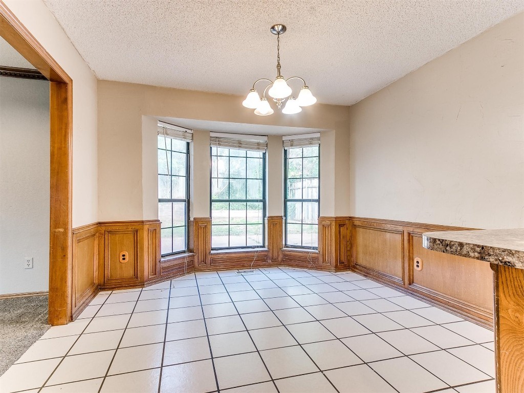613 Cactus Court, Yukon, OK 73099 spare room with a textured ceiling, a notable chandelier, and light tile flooring