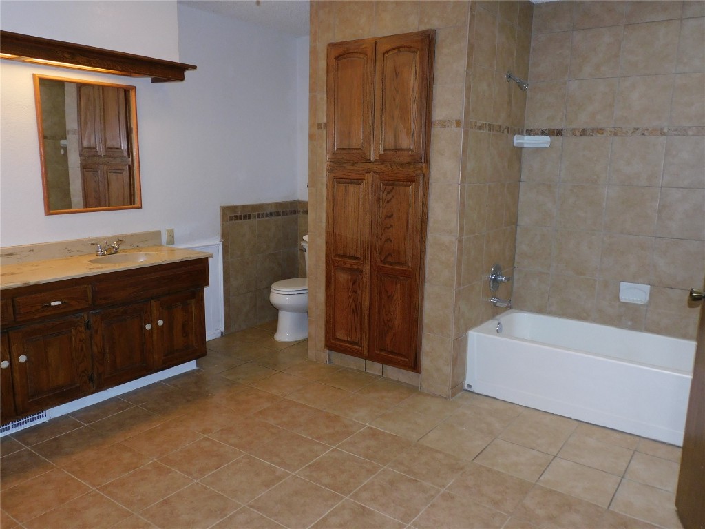 8212 Harvest Hills Road, Oklahoma City, OK 73132 full bathroom with tiled shower / bath combo, toilet, tile floors, and vanity