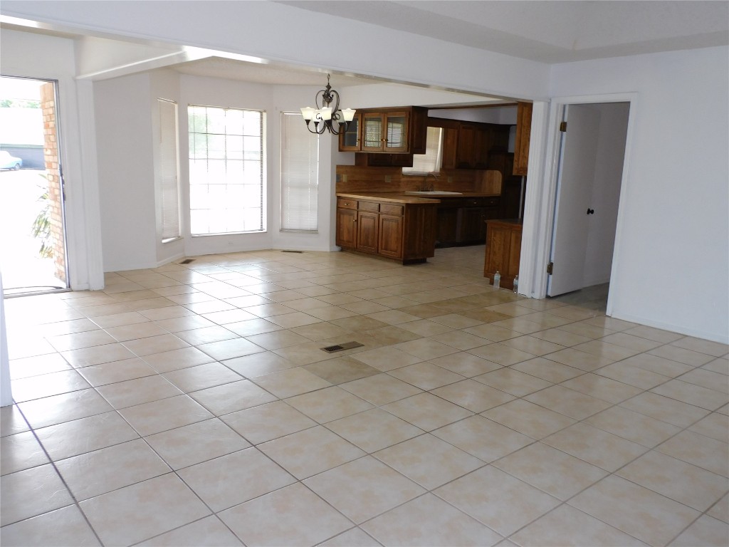 8212 Harvest Hills Road, Oklahoma City, OK 73132 unfurnished living room with sink, light tile flooring, and a chandelier