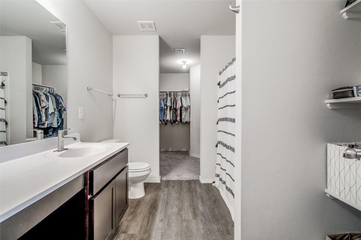 633 W Ava Drive, Mustang, OK 73064 bathroom with hardwood / wood-style floors, oversized vanity, and toilet