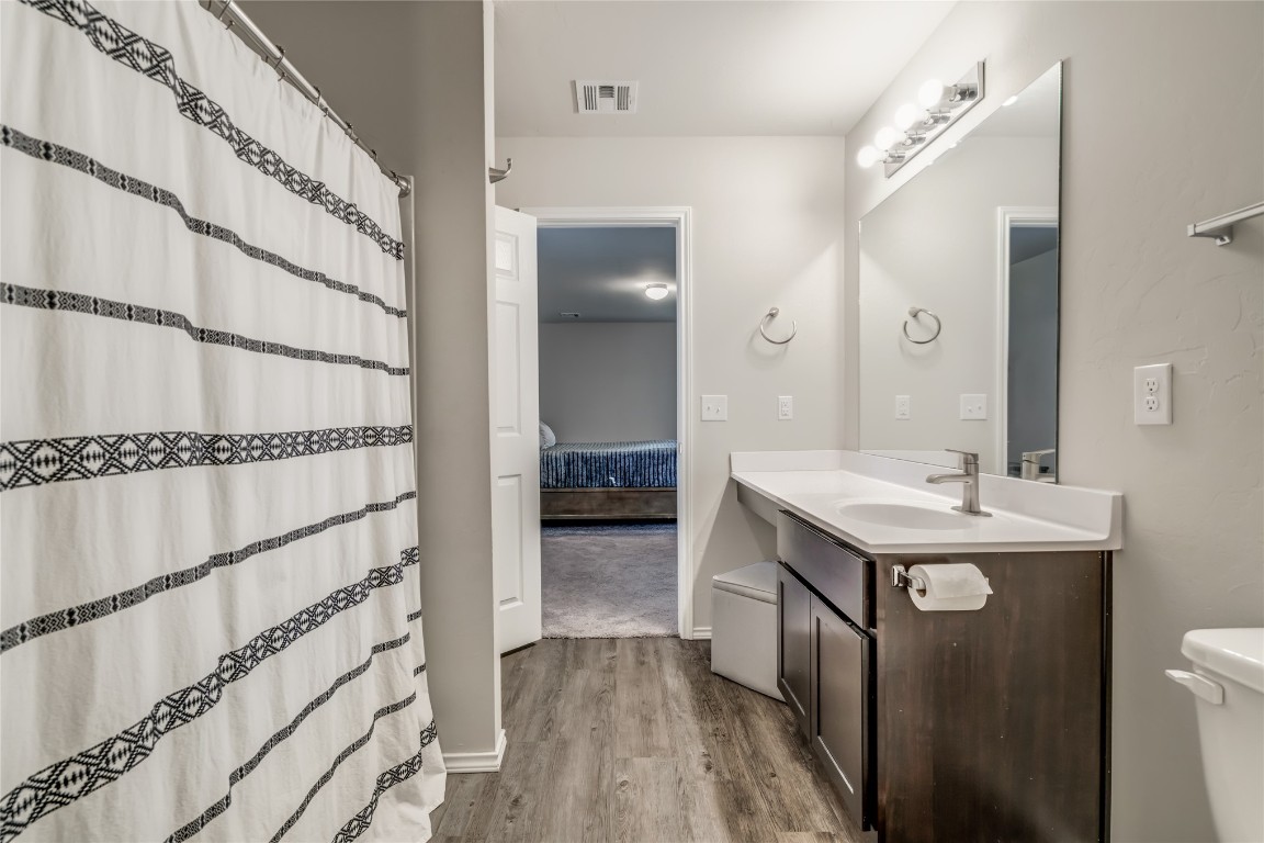 633 W Ava Drive, Mustang, OK 73064 bathroom featuring hardwood / wood-style floors, vanity, and toilet