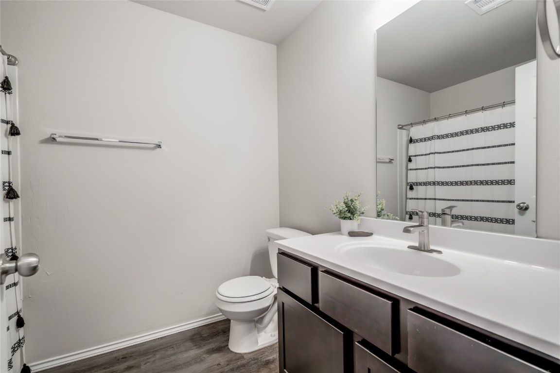 633 W Ava Drive, Mustang, OK 73064 bathroom with toilet, oversized vanity, and hardwood / wood-style floors