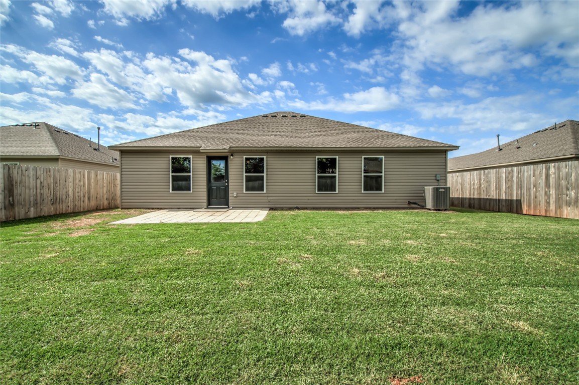 633 W Ava Drive, Mustang, OK 73064 back of house featuring central AC, a patio, and a lawn