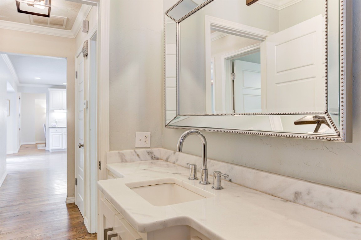 2509 NW 58th Street, Oklahoma City, OK 73112 bathroom with hardwood / wood-style flooring, ornamental molding, and vanity