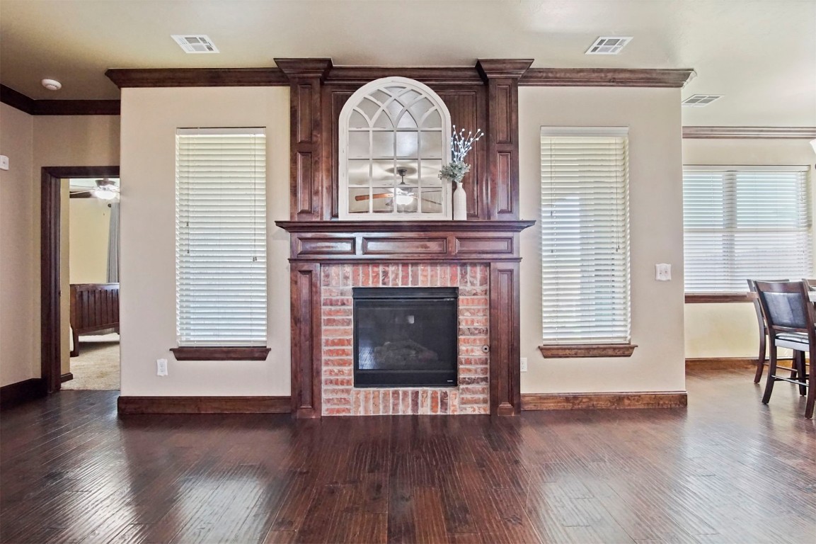 3405 NW 164th Street, Edmond, OK 73013 living room featuring ornamental molding, a brick fireplace, and dark wood-type flooring