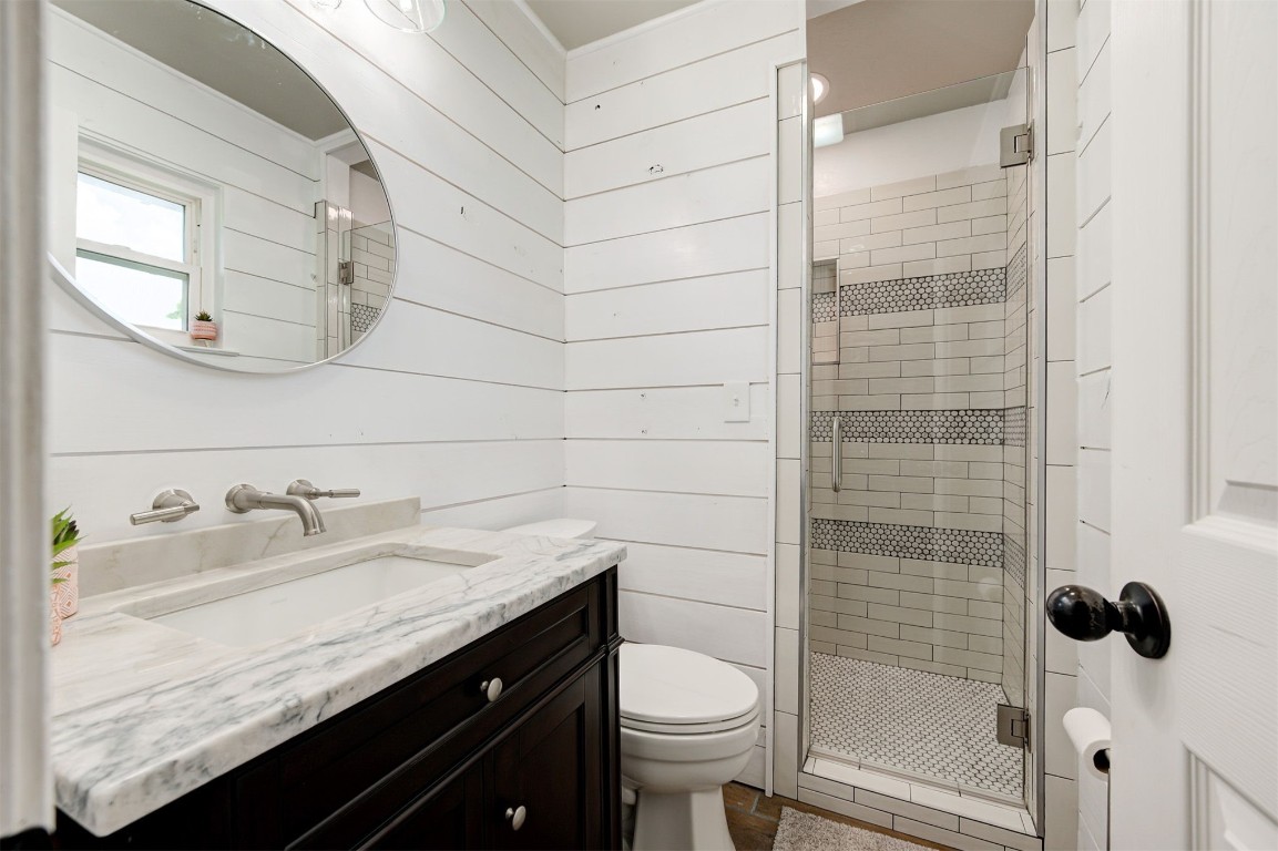 10315 E Post Oak Road, Noble, OK 73068 bathroom featuring walk in shower, wood walls, oversized vanity, and toilet