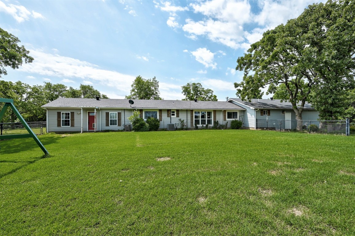 10315 E Post Oak Road, Noble, OK 73068 back of property with a playground, central AC unit, and a lawn